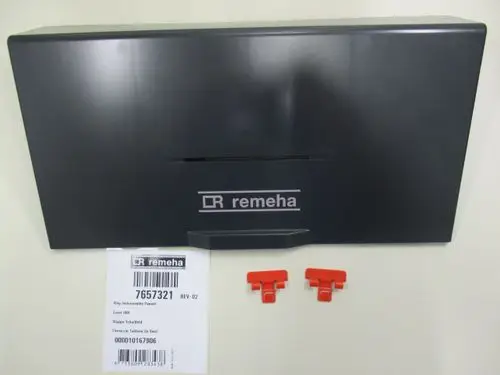 Remeha Klappe für Schaltfeld in grauer Farbe, zusammen mit zwei roten Clips und einem Etikett mit Artikelnummer und weiteren Informationen auf dem Tisch.